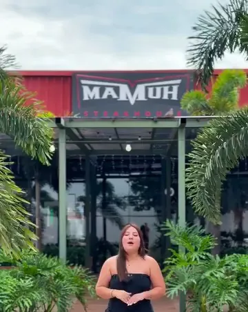 Fachada da Mamuh Steakhouse de dia, com letreiro e jardim
